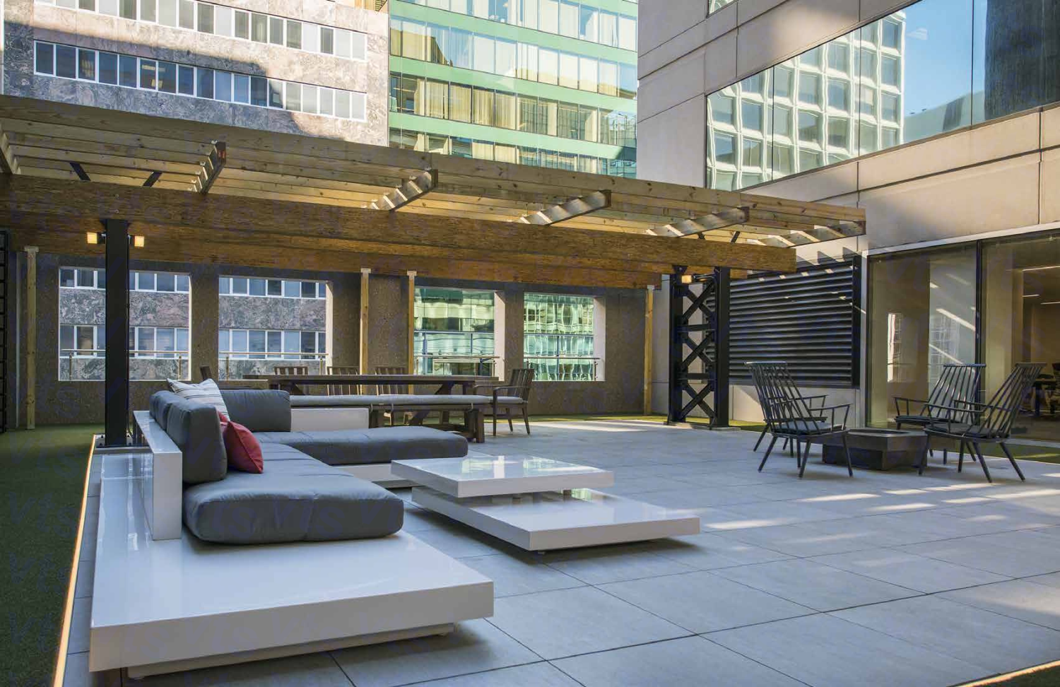 A patio on a building floor with an exposed wooden roof and large modern-design furniture 