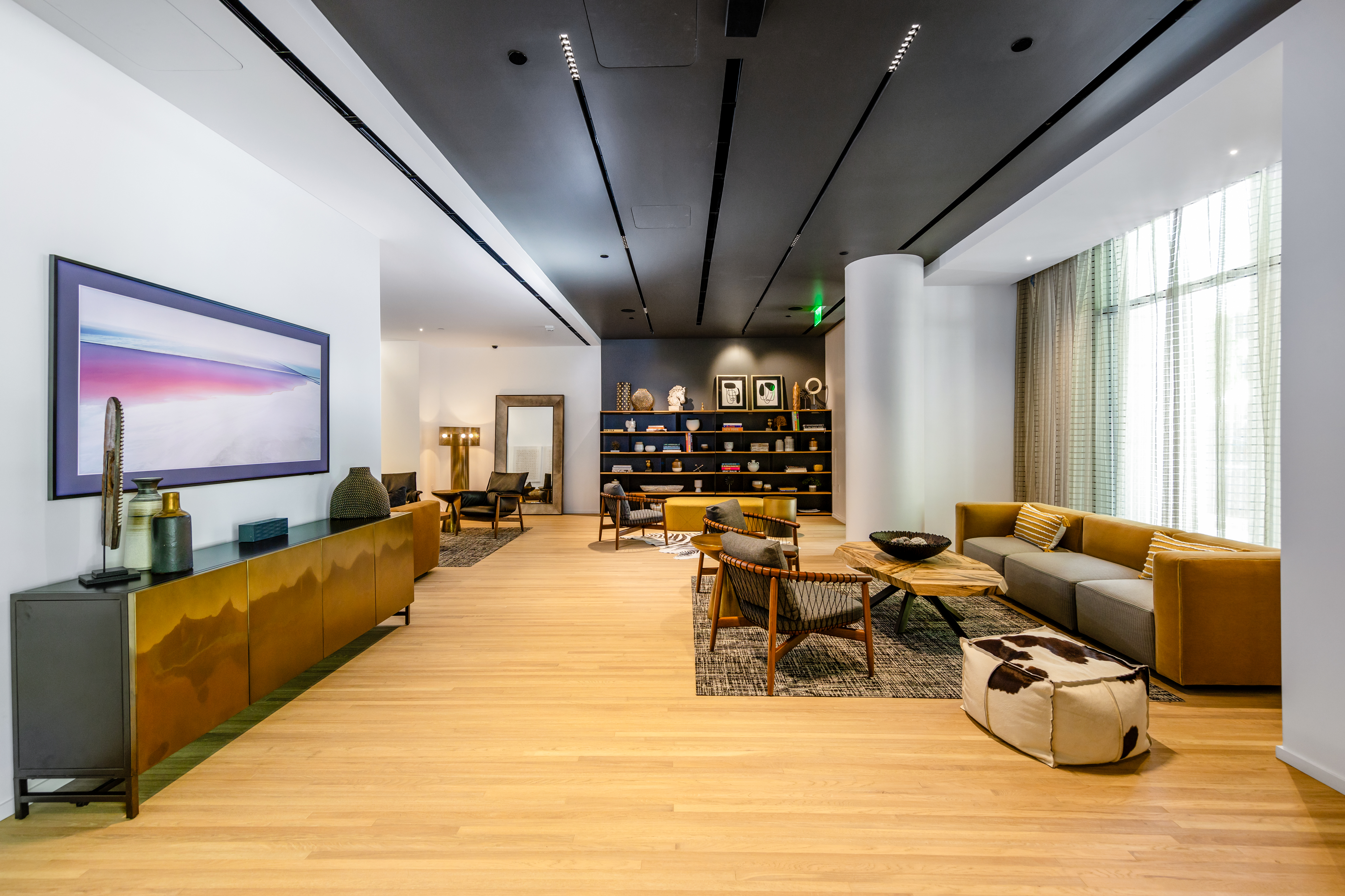 A dimly lit, luxurious lounge with a tufted tan leather sofa, large indoor palm trees, and a striking, illuminated nautilus shell lamp.